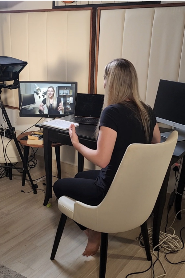 Woman sitting on chair using multiple laptops to prepare for Project Ultimate Life speaking session