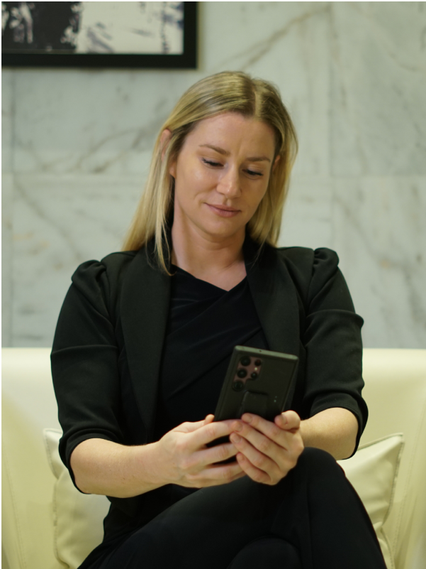 Woman sitting on sofa checking event details on phone
